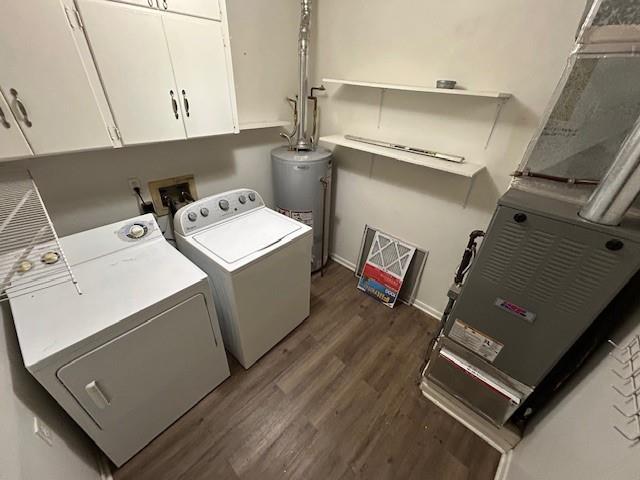 washroom with cabinets, gas water heater, dark hardwood / wood-style floors, heating unit, and washer and clothes dryer