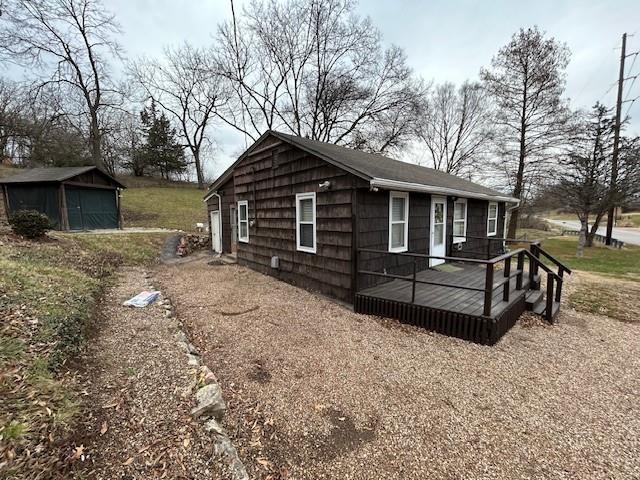 view of home's exterior with a wooden deck, an outbuilding, and a garage