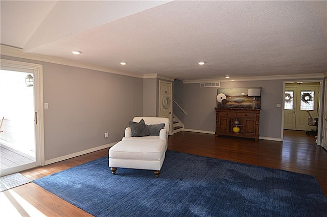 living area with crown molding, dark wood-type flooring, and a textured ceiling