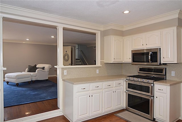 kitchen featuring appliances with stainless steel finishes, dark hardwood / wood-style flooring, decorative backsplash, and white cabinets