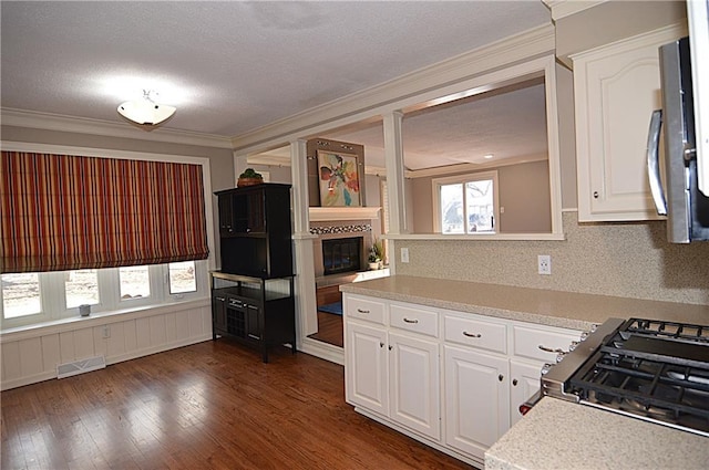 kitchen with tasteful backsplash, gas range, dark hardwood / wood-style floors, and white cabinets