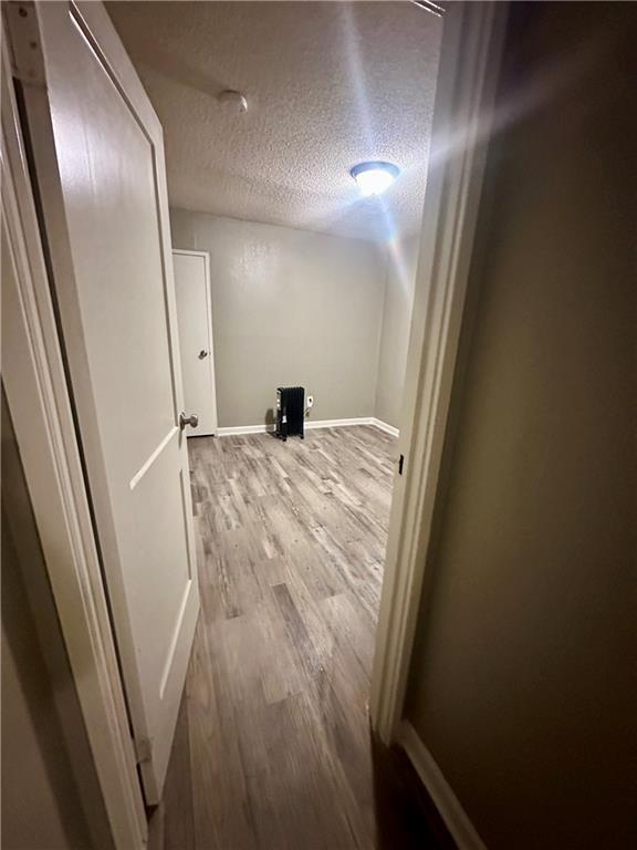 hallway featuring light wood-type flooring and a textured ceiling