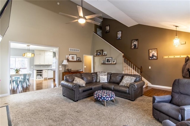 carpeted living room with ceiling fan and vaulted ceiling