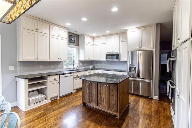 kitchen with stainless steel appliances, sink, white cabinetry, dark hardwood / wood-style floors, and a kitchen island