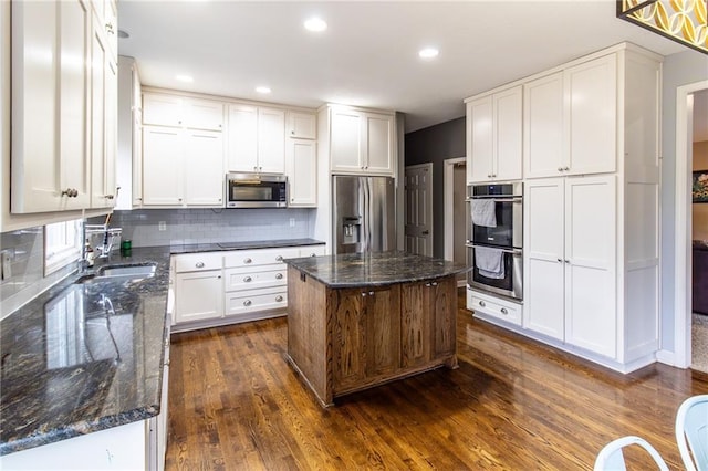 kitchen with white cabinetry, a center island, stainless steel appliances, dark hardwood / wood-style flooring, and dark stone countertops