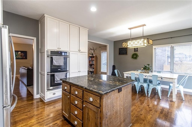 kitchen featuring white cabinetry, a center island, dark stone countertops, pendant lighting, and appliances with stainless steel finishes