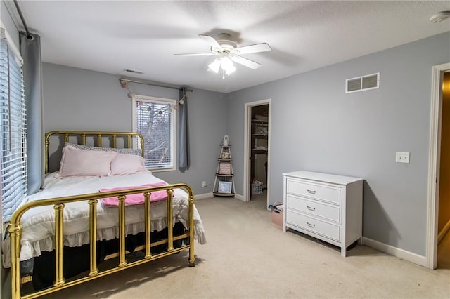 carpeted bedroom with ceiling fan, a spacious closet, and a closet