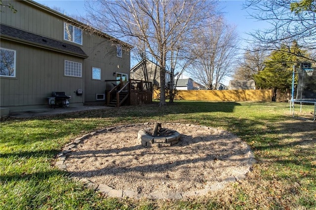 view of yard featuring a trampoline, an outdoor fire pit, a patio area, and a wooden deck