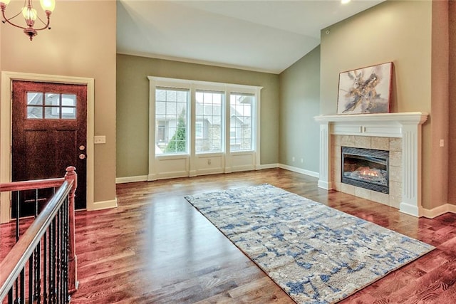 foyer with a fireplace, hardwood / wood-style floors, lofted ceiling, and a notable chandelier