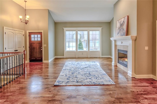 foyer entrance featuring dark hardwood / wood-style flooring, lofted ceiling, a fireplace, and an inviting chandelier