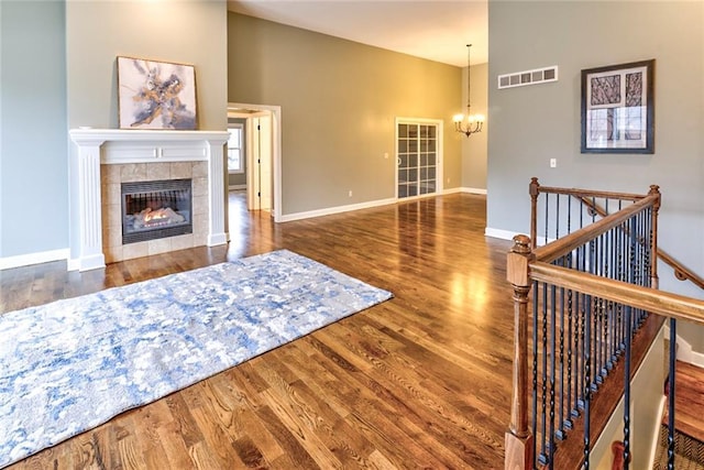 living room with a tile fireplace, a towering ceiling, dark hardwood / wood-style floors, and an inviting chandelier