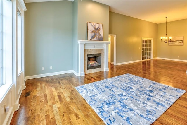 living room featuring a fireplace, wood-type flooring, a chandelier, and a wealth of natural light