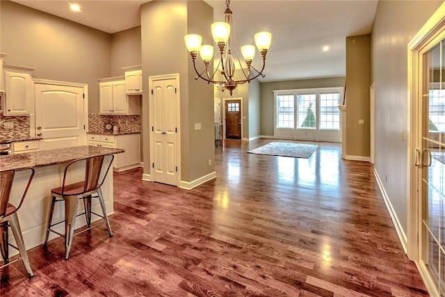 kitchen featuring stone counters, white cabinetry, a notable chandelier, backsplash, and pendant lighting