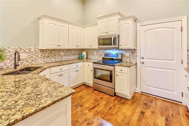 kitchen featuring white cabinets, appliances with stainless steel finishes, light hardwood / wood-style floors, and sink