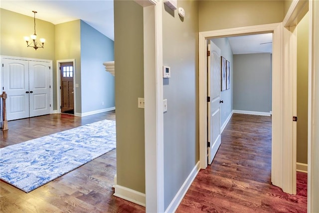 foyer featuring vaulted ceiling, an inviting chandelier, and dark wood-type flooring