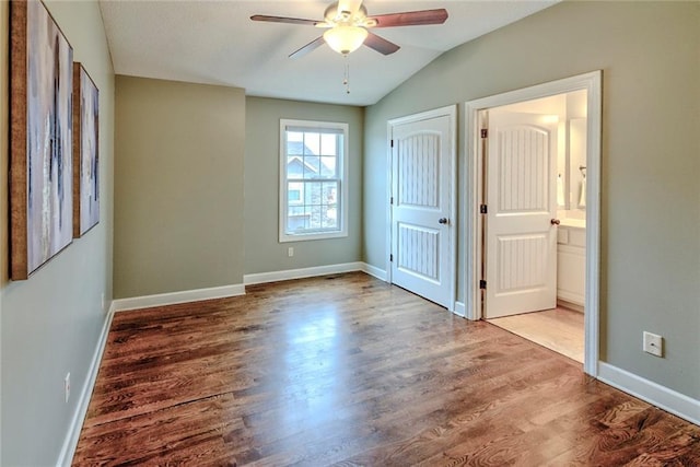 unfurnished bedroom with wood-type flooring, connected bathroom, vaulted ceiling, and ceiling fan