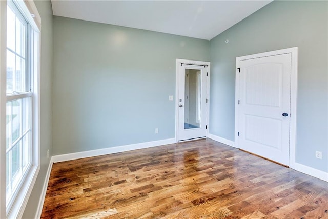 unfurnished room featuring hardwood / wood-style flooring, vaulted ceiling, and a healthy amount of sunlight