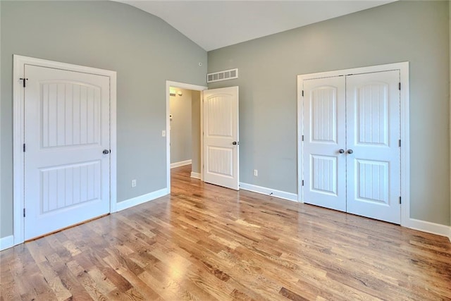 unfurnished bedroom featuring a closet, light hardwood / wood-style floors, and vaulted ceiling