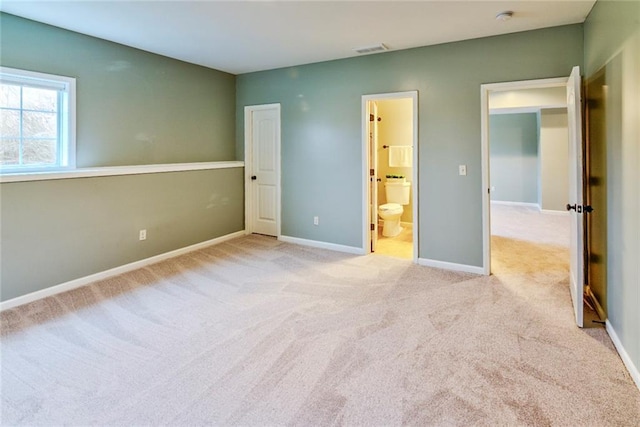 unfurnished bedroom featuring light carpet and ensuite bath