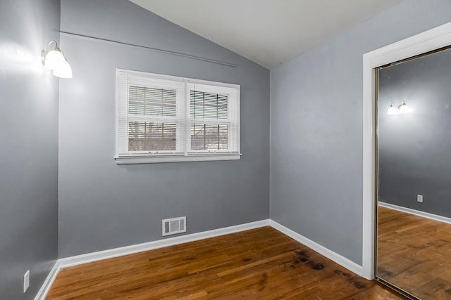 empty room with vaulted ceiling and dark wood-type flooring