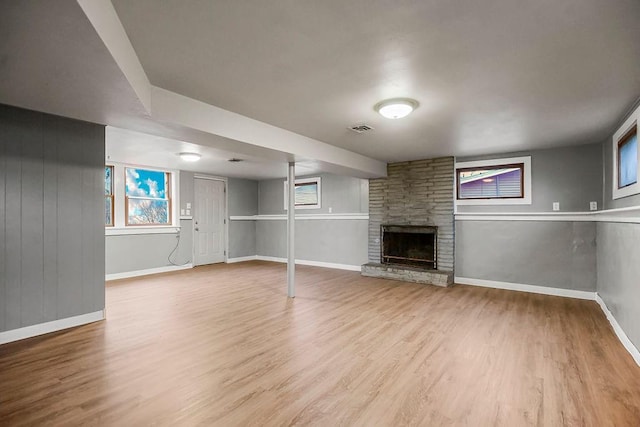 basement featuring light hardwood / wood-style floors and a stone fireplace