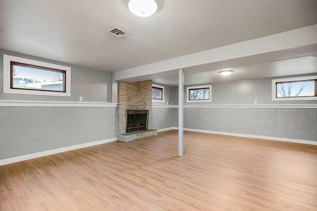 basement with a large fireplace and light wood-type flooring