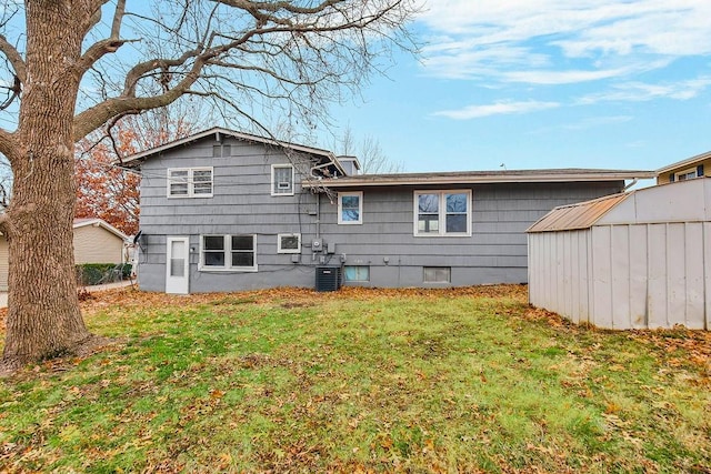 back of house with a lawn, a storage unit, and central AC