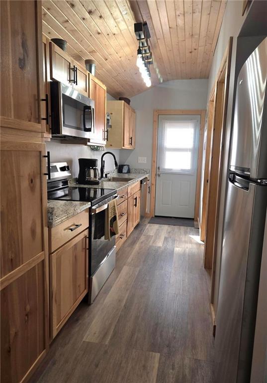 kitchen featuring appliances with stainless steel finishes, light stone counters, dark wood-type flooring, sink, and wooden ceiling