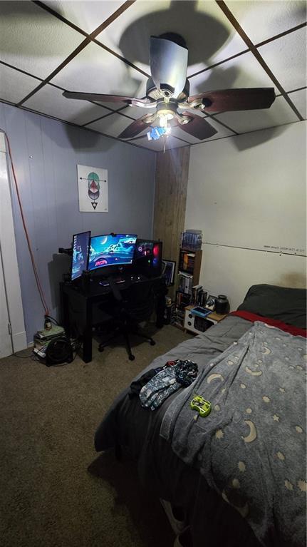 carpeted bedroom with a paneled ceiling and ceiling fan