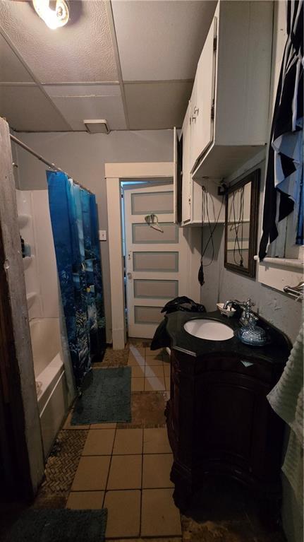 bathroom featuring tile patterned flooring, shower / bath combination with curtain, a paneled ceiling, and vanity