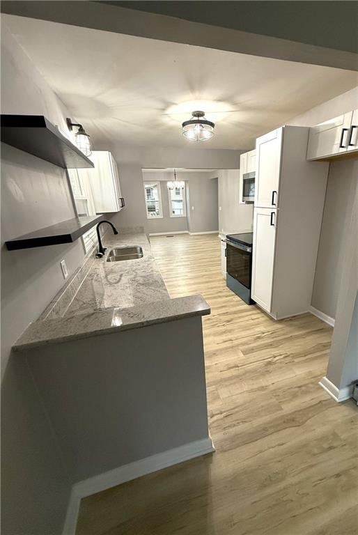 kitchen featuring white cabinetry, sink, black range with electric cooktop, dark stone countertops, and a chandelier