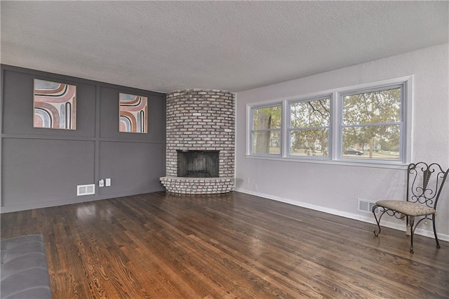 living room with a fireplace, dark hardwood / wood-style floors, and a textured ceiling