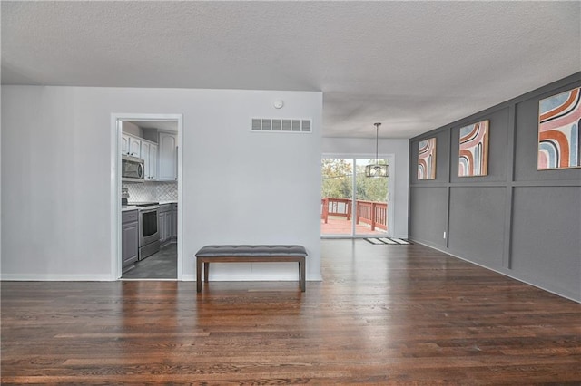 spare room featuring dark hardwood / wood-style flooring, a chandelier, and a textured ceiling