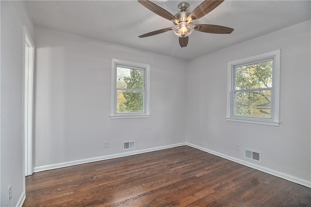 spare room with ceiling fan, plenty of natural light, and dark wood-type flooring