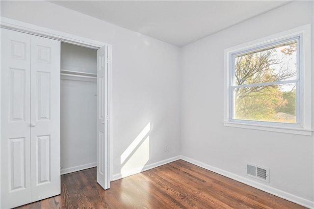 unfurnished bedroom featuring a closet and dark hardwood / wood-style floors