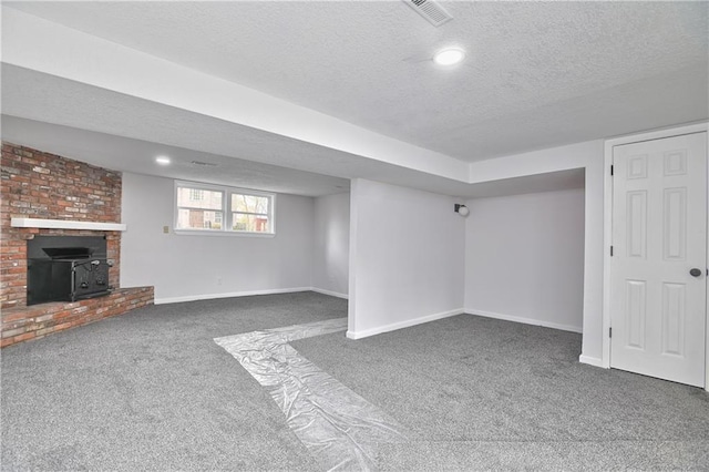 basement featuring dark carpet, a textured ceiling, and a wood stove