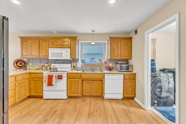 kitchen with tasteful backsplash, white appliances, sink, washer / dryer, and hanging light fixtures