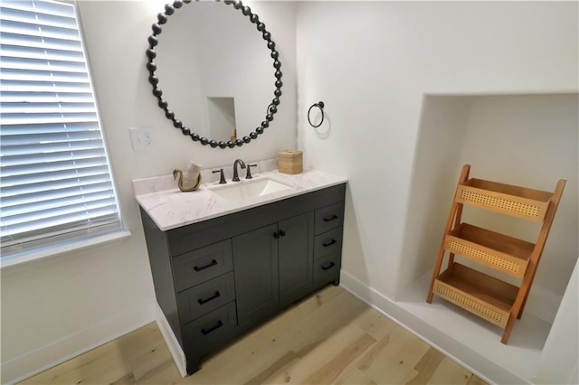 bathroom featuring baseboards, wood finished floors, and vanity