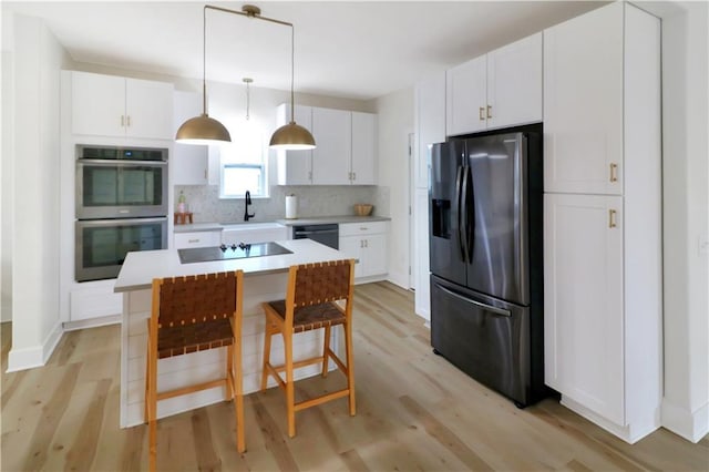 kitchen with black appliances, white cabinetry, decorative backsplash, and light countertops