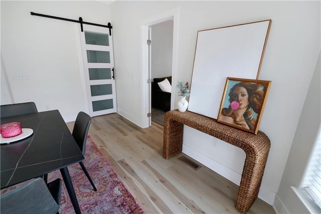 home office featuring a barn door, wood finished floors, and visible vents