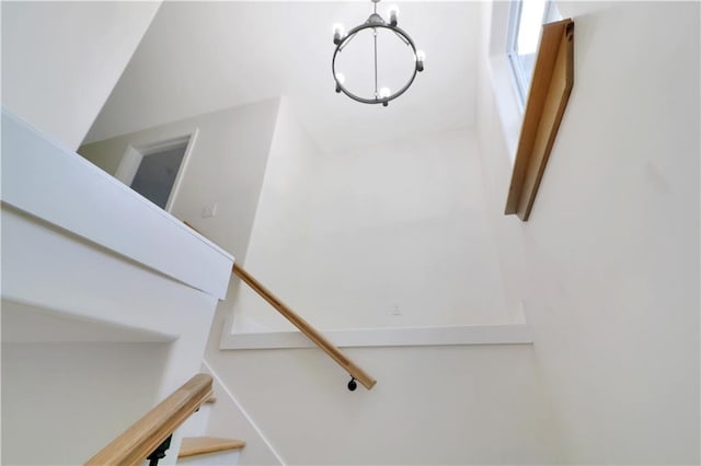 staircase with an inviting chandelier