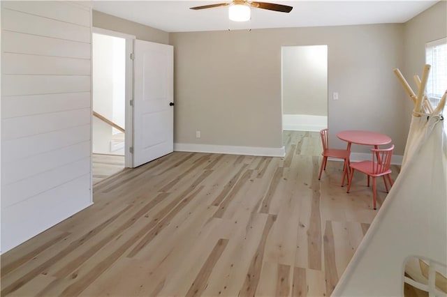 interior space with wood finished floors, a ceiling fan, and baseboards