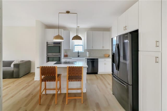 kitchen with a breakfast bar, white cabinetry, a kitchen island, pendant lighting, and black appliances