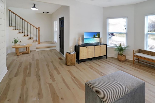 living area featuring stairway, light wood-style flooring, and baseboards