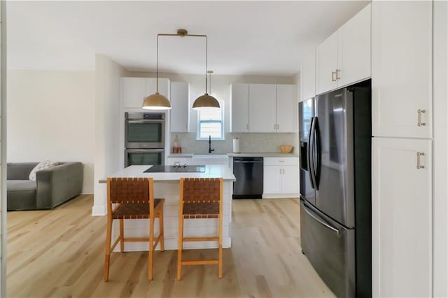 411 Charles, Warrensburg, MO 64093 - kitchen with black appliances, light wood-style floors, light countertops, backsplash, and a breakfast bar area