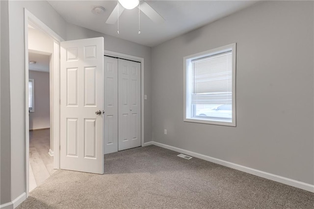 unfurnished bedroom with ceiling fan, a closet, and light carpet