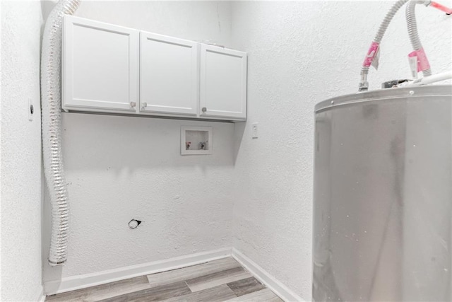 laundry area with electric water heater, light hardwood / wood-style flooring, and cabinets