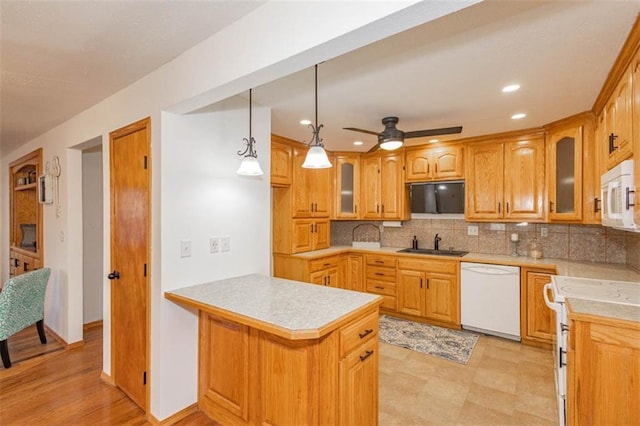 kitchen featuring sink, decorative light fixtures, kitchen peninsula, white appliances, and decorative backsplash