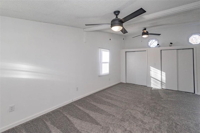 unfurnished bedroom featuring multiple windows, two closets, a textured ceiling, and carpet