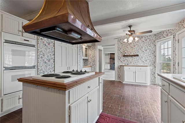 kitchen with island range hood, white appliances, white cabinetry, and a kitchen island